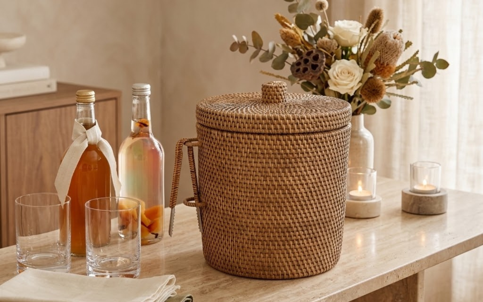 Handwoven rattan ice bucket with tongs on an entertaining table